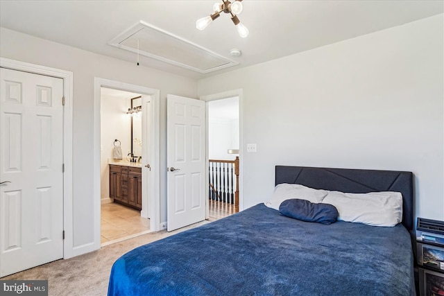 bedroom featuring attic access, baseboards, ensuite bathroom, and light carpet