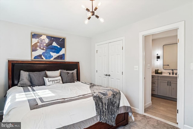 bedroom featuring baseboards, a sink, a closet, a notable chandelier, and light colored carpet