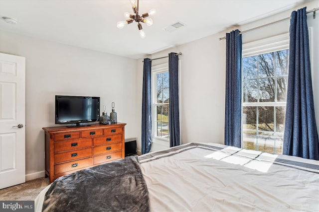 carpeted bedroom featuring a notable chandelier, visible vents, and baseboards