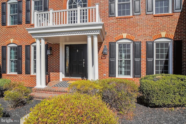 property entrance with brick siding and a balcony