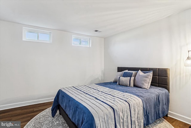 bedroom with visible vents, baseboards, and wood finished floors