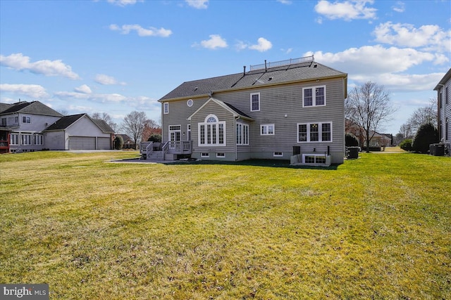 back of house with central air condition unit, a lawn, and a garage