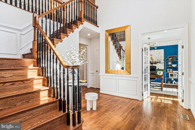 foyer entrance featuring a decorative wall, stairway, visible vents, and wood finished floors