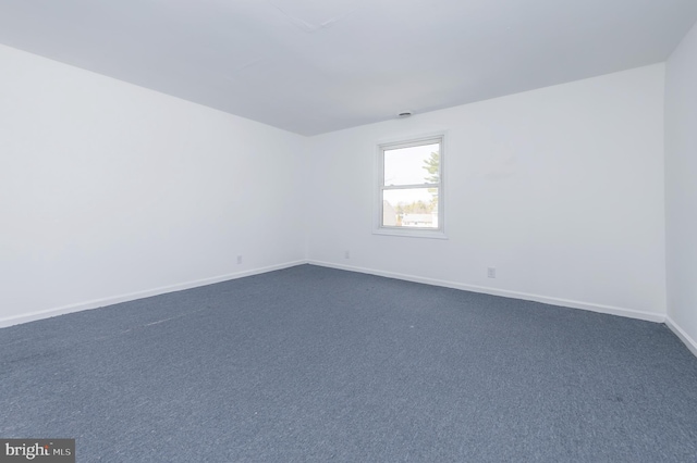 empty room with baseboards and dark carpet