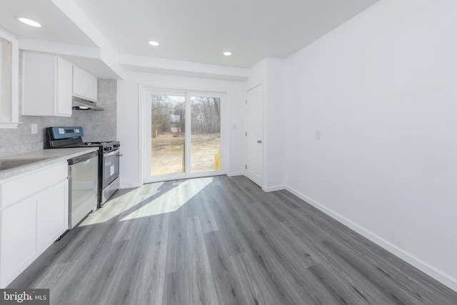 kitchen with stainless steel appliances, under cabinet range hood, white cabinetry, tasteful backsplash, and light wood-type flooring