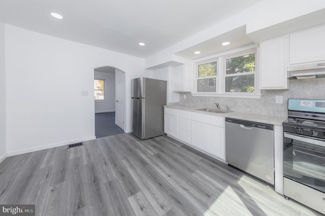 kitchen with visible vents, arched walkways, a sink, stainless steel appliances, and white cabinetry