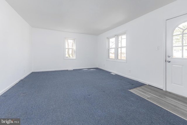 entryway with dark carpet, baseboards, and a wealth of natural light