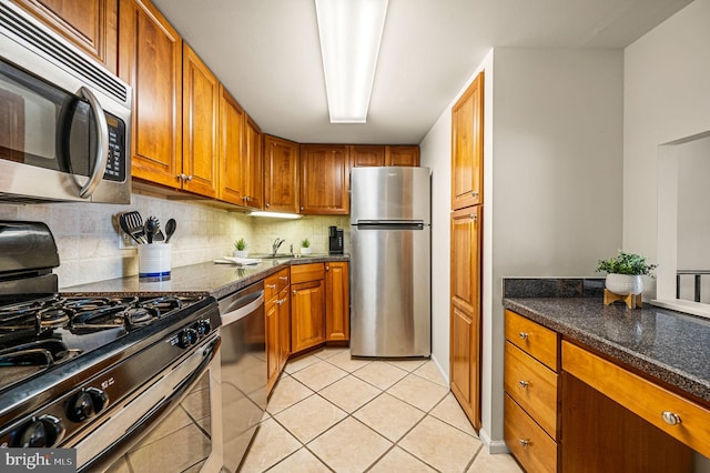 kitchen with light tile patterned floors, decorative backsplash, brown cabinets, and appliances with stainless steel finishes