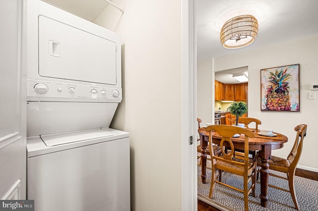 laundry area with laundry area, baseboards, and stacked washer / drying machine