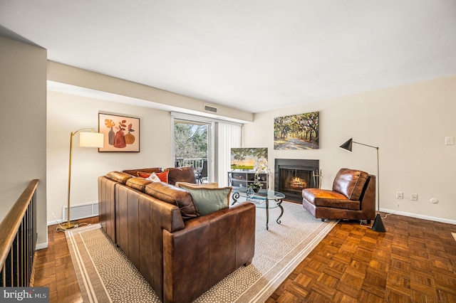 living area featuring visible vents, baseboards, and a lit fireplace