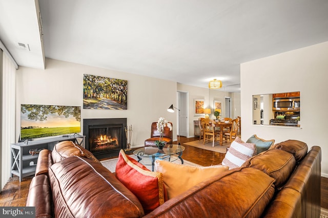 living area featuring visible vents and a fireplace with flush hearth