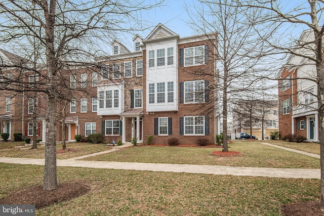 townhome / multi-family property with brick siding and a front lawn