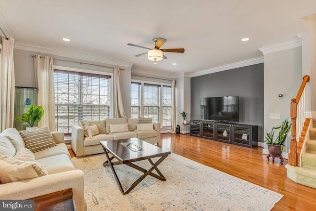 living area with stairs, ornamental molding, wood finished floors, and ceiling fan