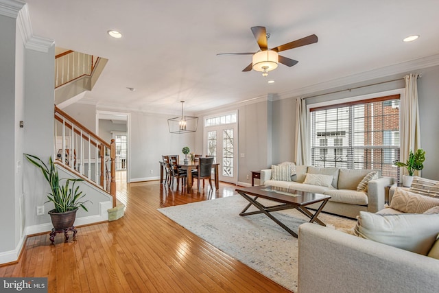 living room with stairway, light wood-style flooring, and crown molding