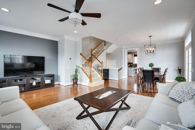 living room with wood finished floors, recessed lighting, stairway, crown molding, and baseboards