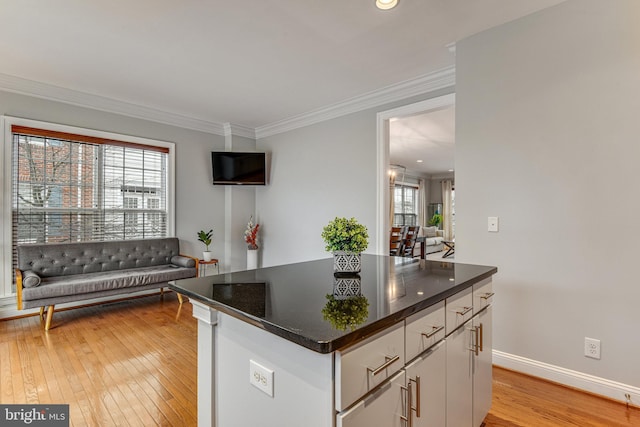 kitchen featuring light wood-style flooring, ornamental molding, a center island, white cabinetry, and baseboards