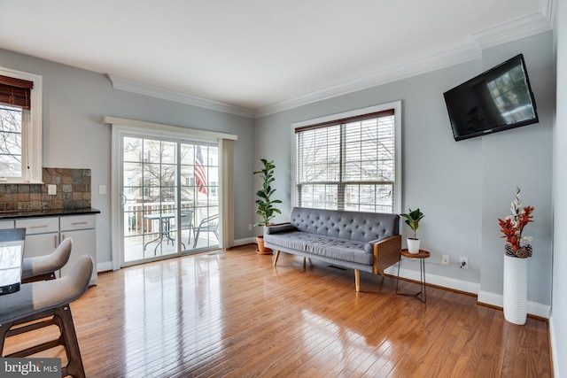 sitting room with baseboards, light wood-style floors, and crown molding