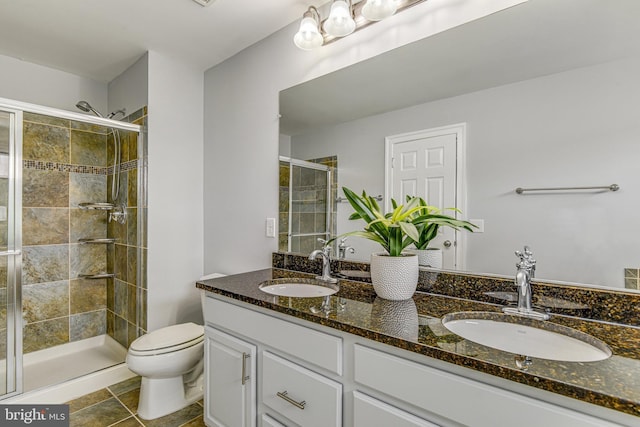 full bath with double vanity, toilet, a stall shower, and a sink