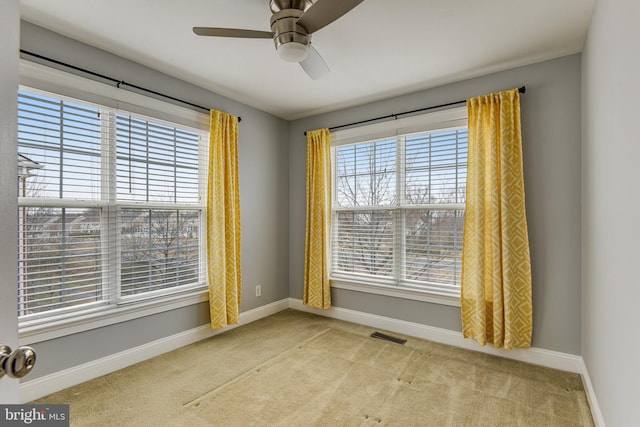 carpeted empty room featuring visible vents, baseboards, and ceiling fan