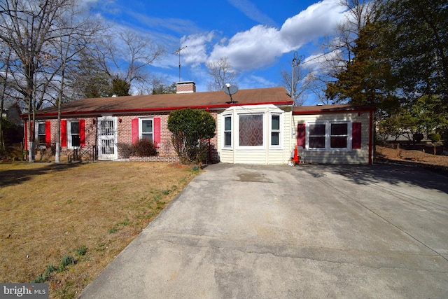 ranch-style home with brick siding, a chimney, and a front lawn