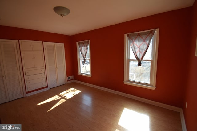 unfurnished bedroom with a closet, visible vents, baseboards, and wood finished floors