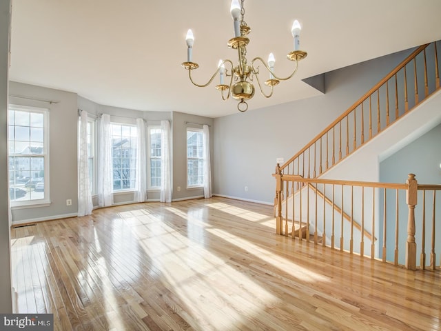 interior space with plenty of natural light, wood finished floors, baseboards, and a chandelier