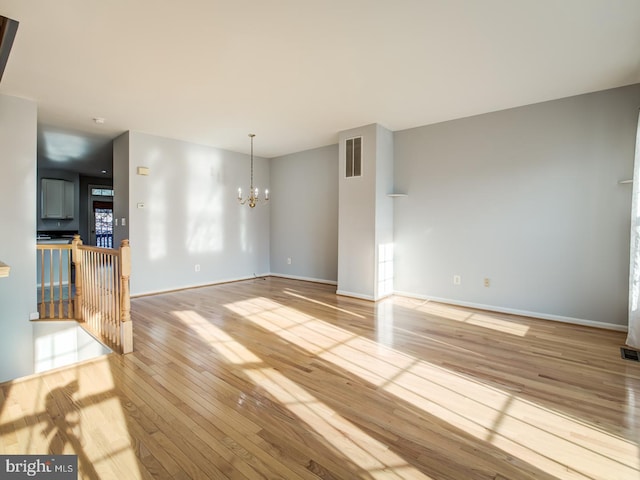 interior space with hardwood / wood-style floors, an inviting chandelier, baseboards, and visible vents