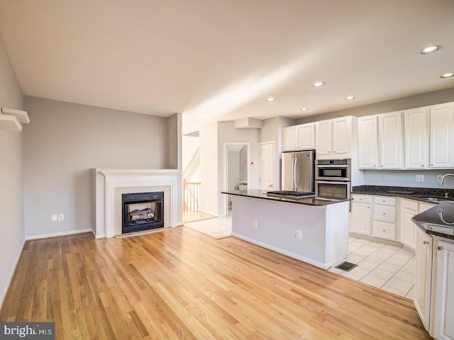 kitchen featuring a sink, a center island, light wood-style floors, appliances with stainless steel finishes, and white cabinets