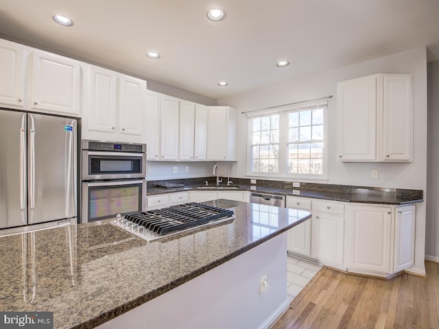 kitchen with dark stone counters, recessed lighting, a sink, white cabinets, and appliances with stainless steel finishes