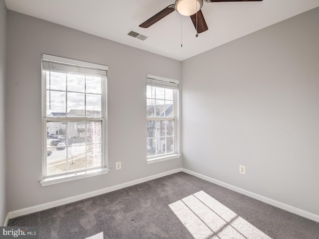 carpeted spare room featuring visible vents, ceiling fan, and baseboards