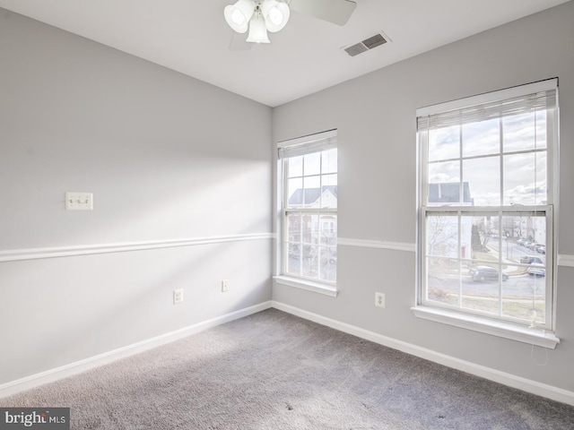 carpeted spare room with a ceiling fan, baseboards, and visible vents