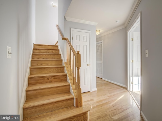 stairway featuring crown molding, wood finished floors, and baseboards