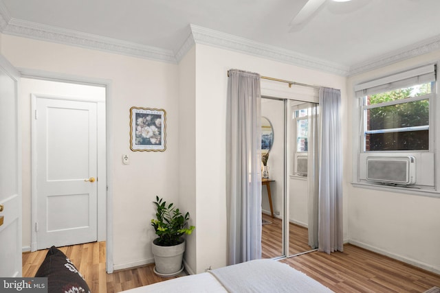 bedroom with crown molding, baseboards, ceiling fan, light wood-style flooring, and cooling unit