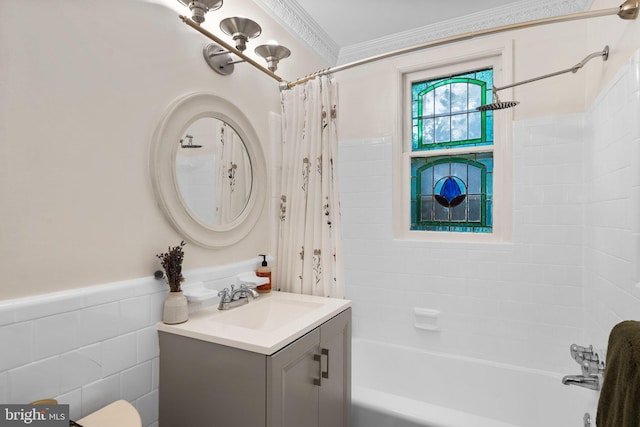 bathroom featuring a wainscoted wall, shower / tub combo with curtain, ornamental molding, tile walls, and vanity