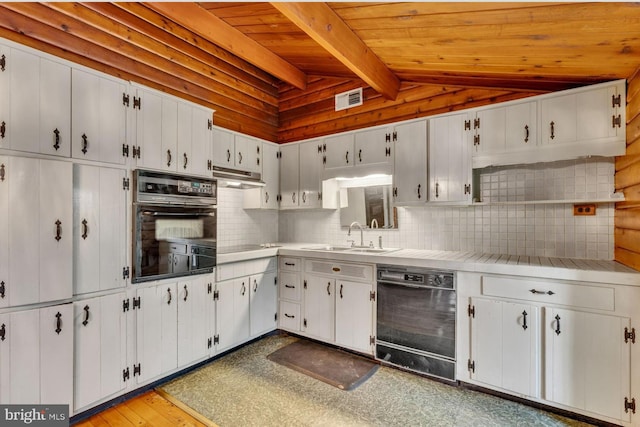 kitchen with visible vents, vaulted ceiling with beams, under cabinet range hood, black appliances, and a sink