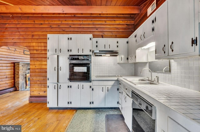 kitchen with a sink, decorative backsplash, black appliances, wood ceiling, and under cabinet range hood