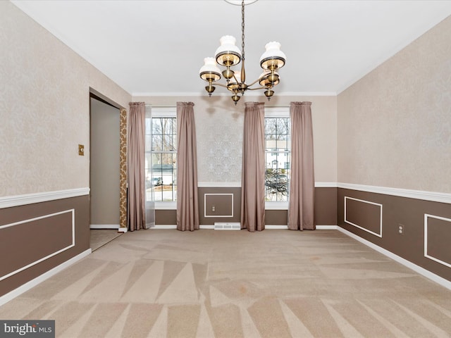 unfurnished dining area with plenty of natural light, carpet, an inviting chandelier, and a wainscoted wall