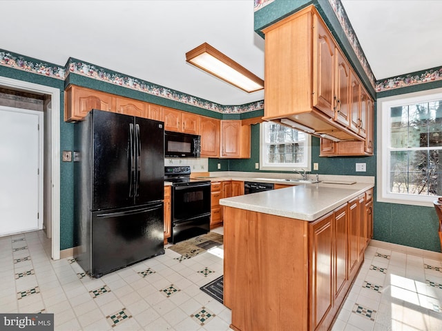 kitchen with black appliances, plenty of natural light, a peninsula, and light countertops