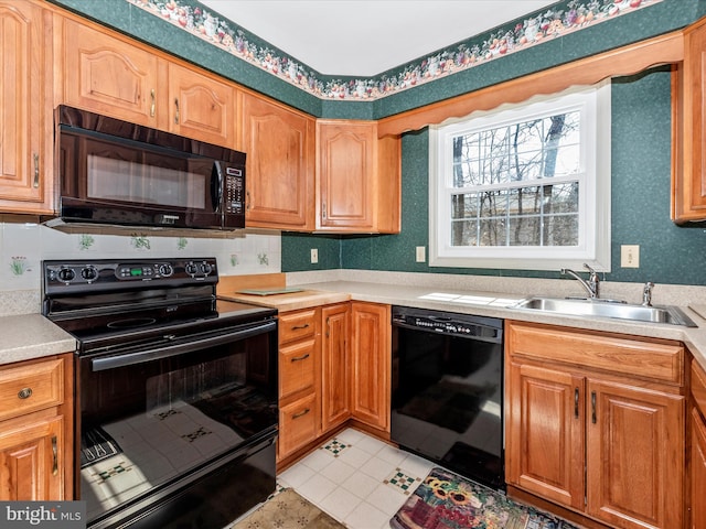 kitchen featuring a sink, wallpapered walls, black appliances, and light countertops