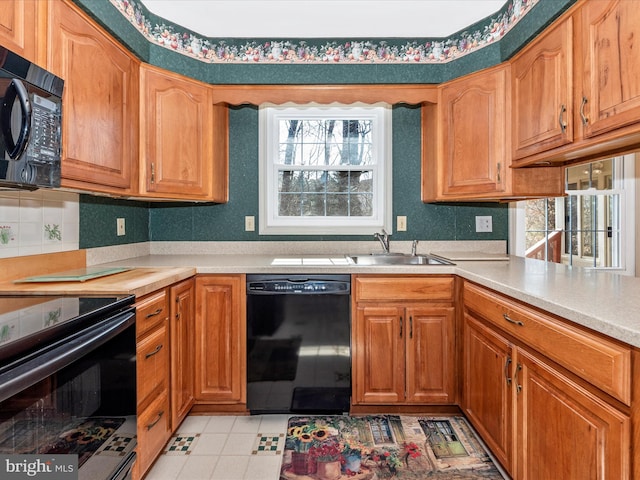 kitchen featuring plenty of natural light, black appliances, light countertops, and a sink