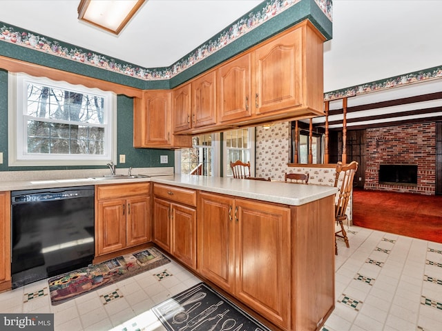 kitchen with a brick fireplace, dishwasher, light countertops, a peninsula, and a sink