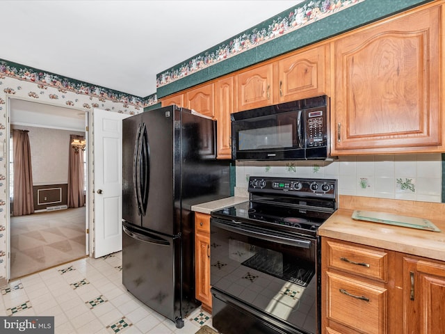 kitchen with wallpapered walls, black appliances, light floors, and tasteful backsplash