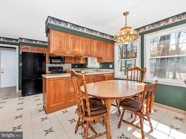 kitchen featuring wallpapered walls, black appliances, and light countertops