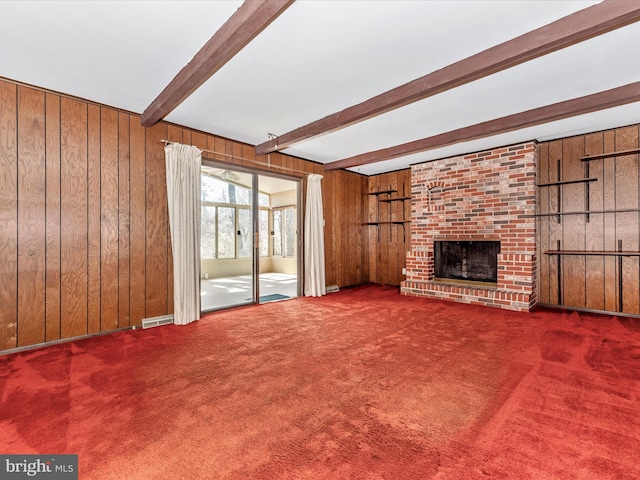 unfurnished living room featuring wooden walls, visible vents, a brick fireplace, beam ceiling, and carpet flooring