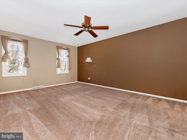 carpeted spare room featuring baseboards, a ceiling fan, visible vents, and a healthy amount of sunlight