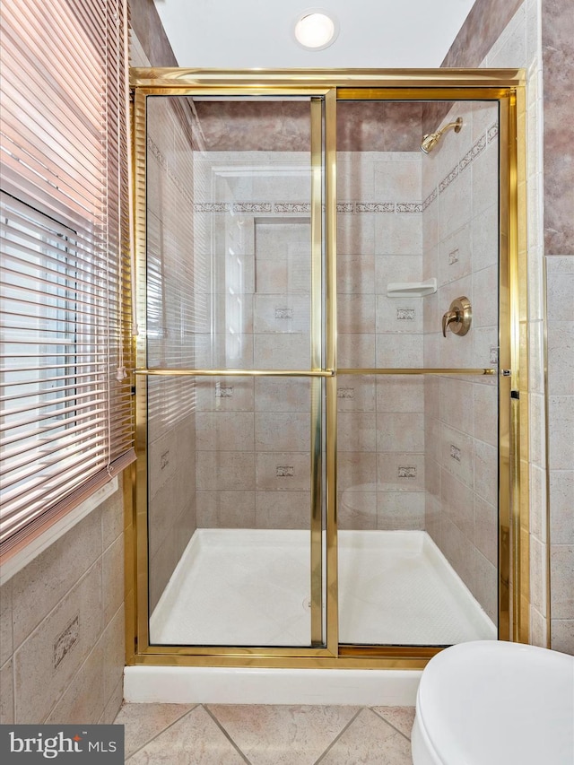 full bathroom with tile patterned floors, a shower stall, toilet, and tile walls