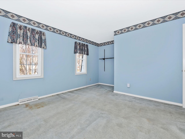 carpeted spare room featuring visible vents and baseboards