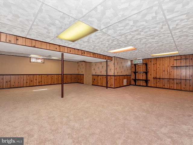 basement featuring a wainscoted wall, carpet floors, visible vents, and wood walls