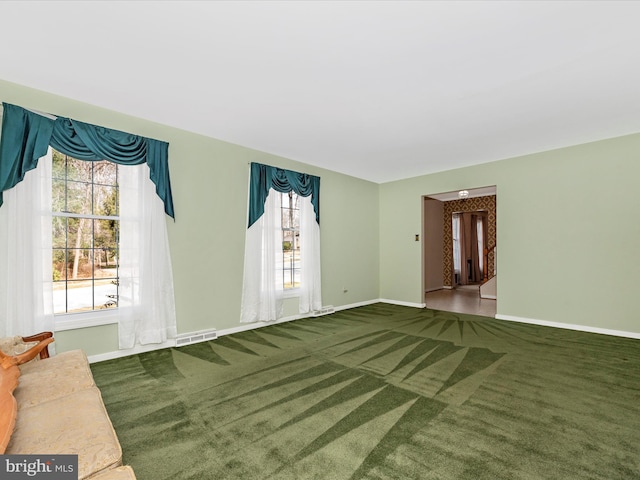 unfurnished living room with carpet, visible vents, and baseboards