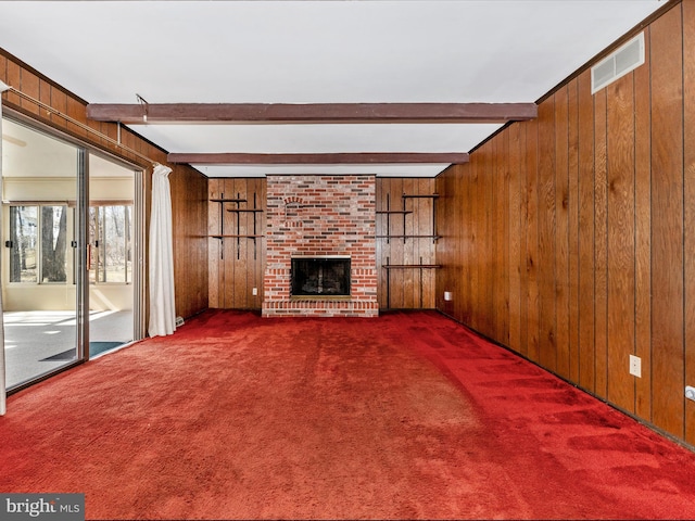 unfurnished living room with wooden walls, carpet, and visible vents